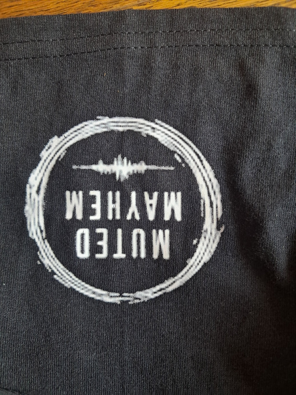 The muted mayhem circle logo print on the black sleeve promoting mental health and neurodivergence awareness by muted mayhem.
