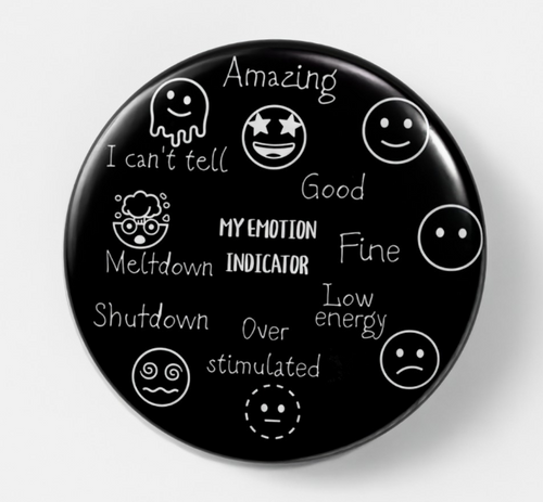 A round black button badge featuring white text and emoji-style drawings that label different emotion states, including Amazing, Good, Fine, Low energy, Over stimulated, Shutdown, Meltdown, and I can't tell. The center reads 'MY EMOTION INDICATOR'.