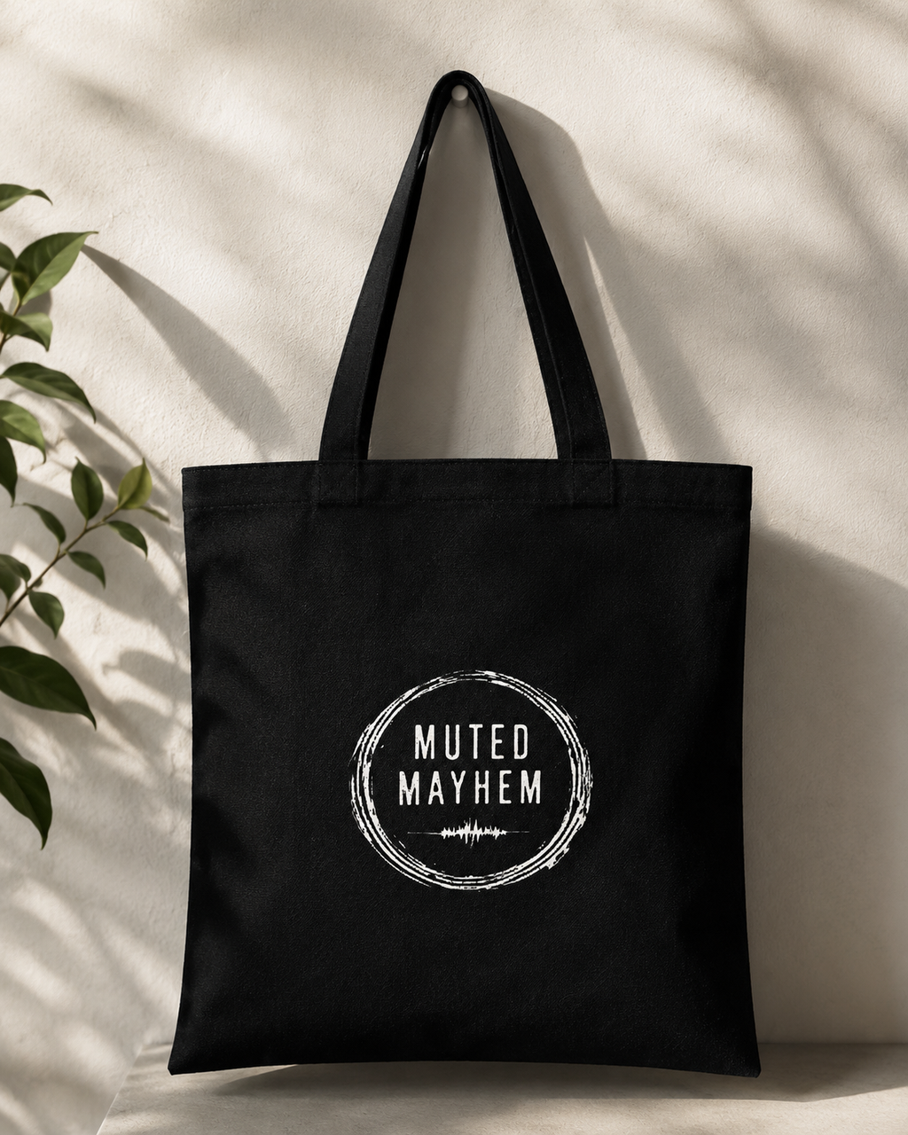 Black tote bag with 'Muted Mayhem' logo on a light background promoting mental health and neurodivergence awareness by muted mayhem.