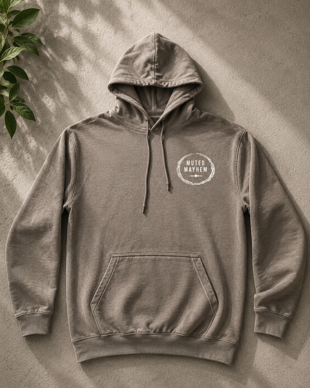 Gray hoodie with a logo on a textured surface promoting mental health and neurodivergence awareness by muted mayhem 