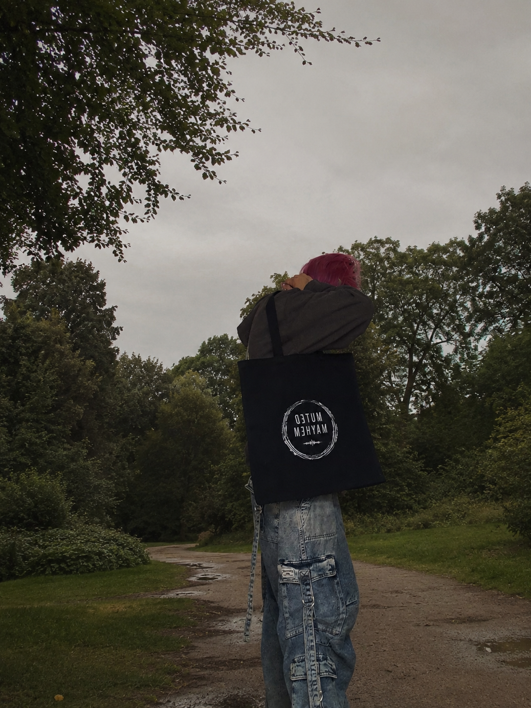 Person walking on a path with a bag over their shoulder in a forested area promoting mental health and neurodivergence awareness by muted mayhem.