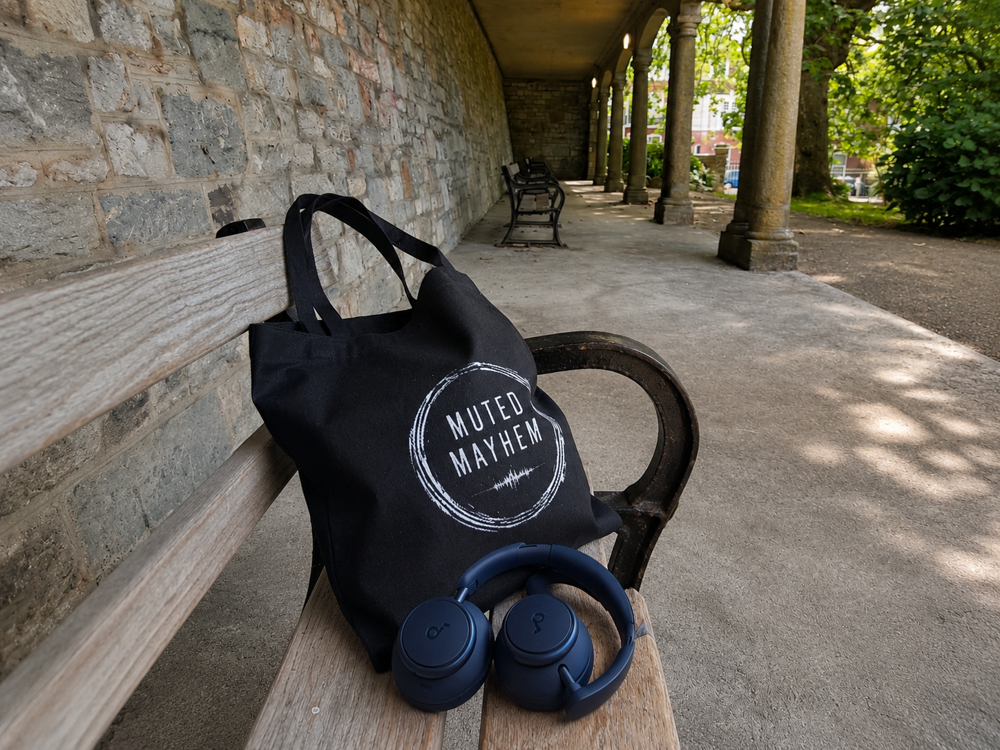 Black tote bag with 'Muted Mayhem' text on a bench outdoors promoting mental health and neurodivergence awareness by muted mayhem.