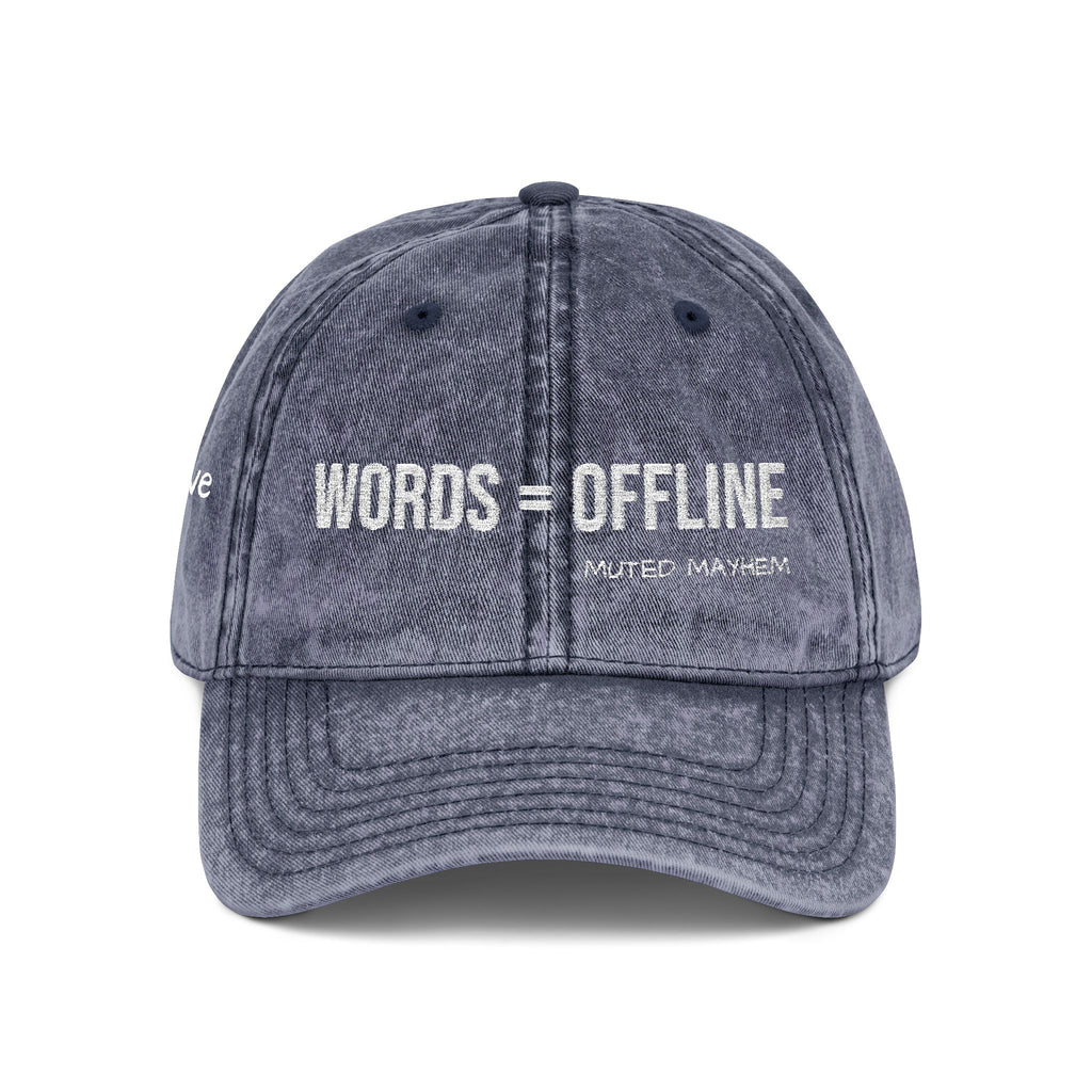 A washed charcoal gray baseball cap with white embroidered text reading 'WORDS = OFFLINE' and 'MUTED MAYHEM' on the front, shown against a plain white background.