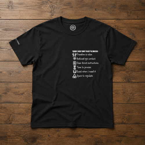 A black short-sleeve crewneck t-shirt with a white graphic print on the left chest, laid flat on a dark brown wooden plank background.