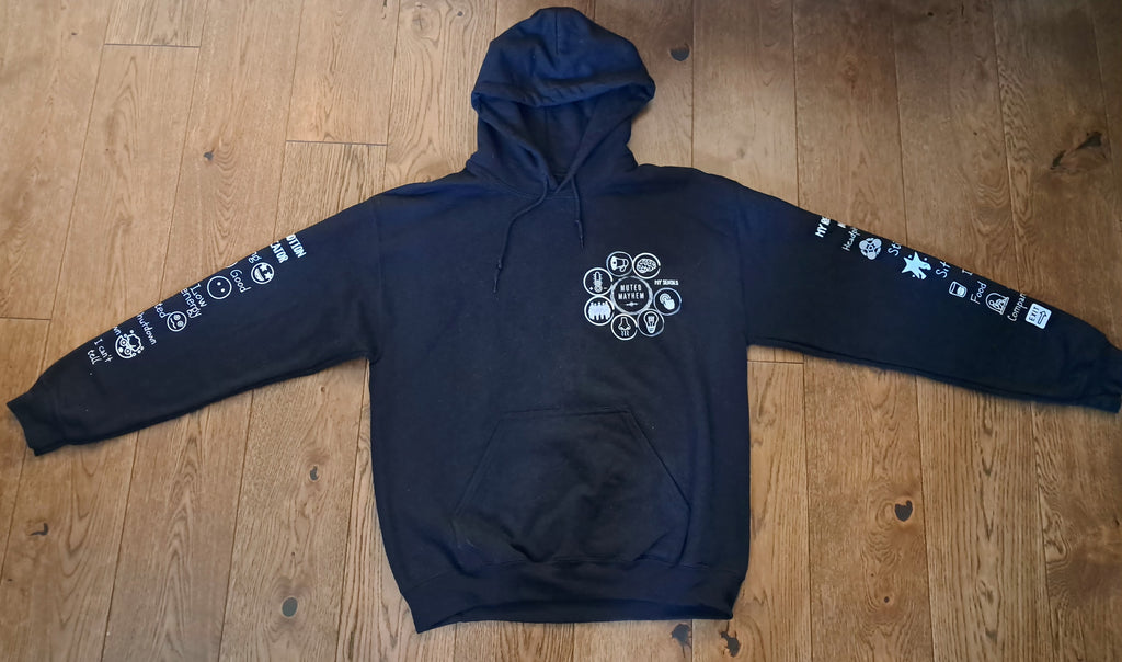 A black pullover hoodie with white graphic prints on the chest and both sleeves, laid flat on a wooden floor.