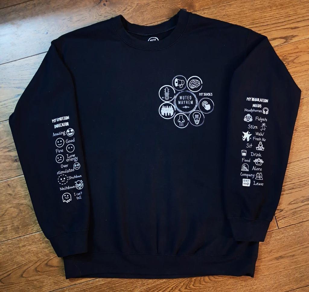 A black crewneck sweatshirt with white graphic prints on the chest and both sleeves, laid flat on a wooden floor.