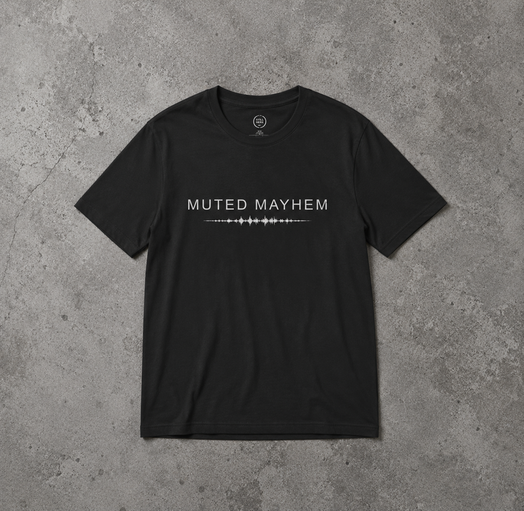 A black short-sleeve t-shirt with 'MUTED MAYHEM' and a soundwave graphic printed in white across the chest, laid flat on a textured gray concrete background promoting mental health and neurodivergence awareness by muted mayhem.