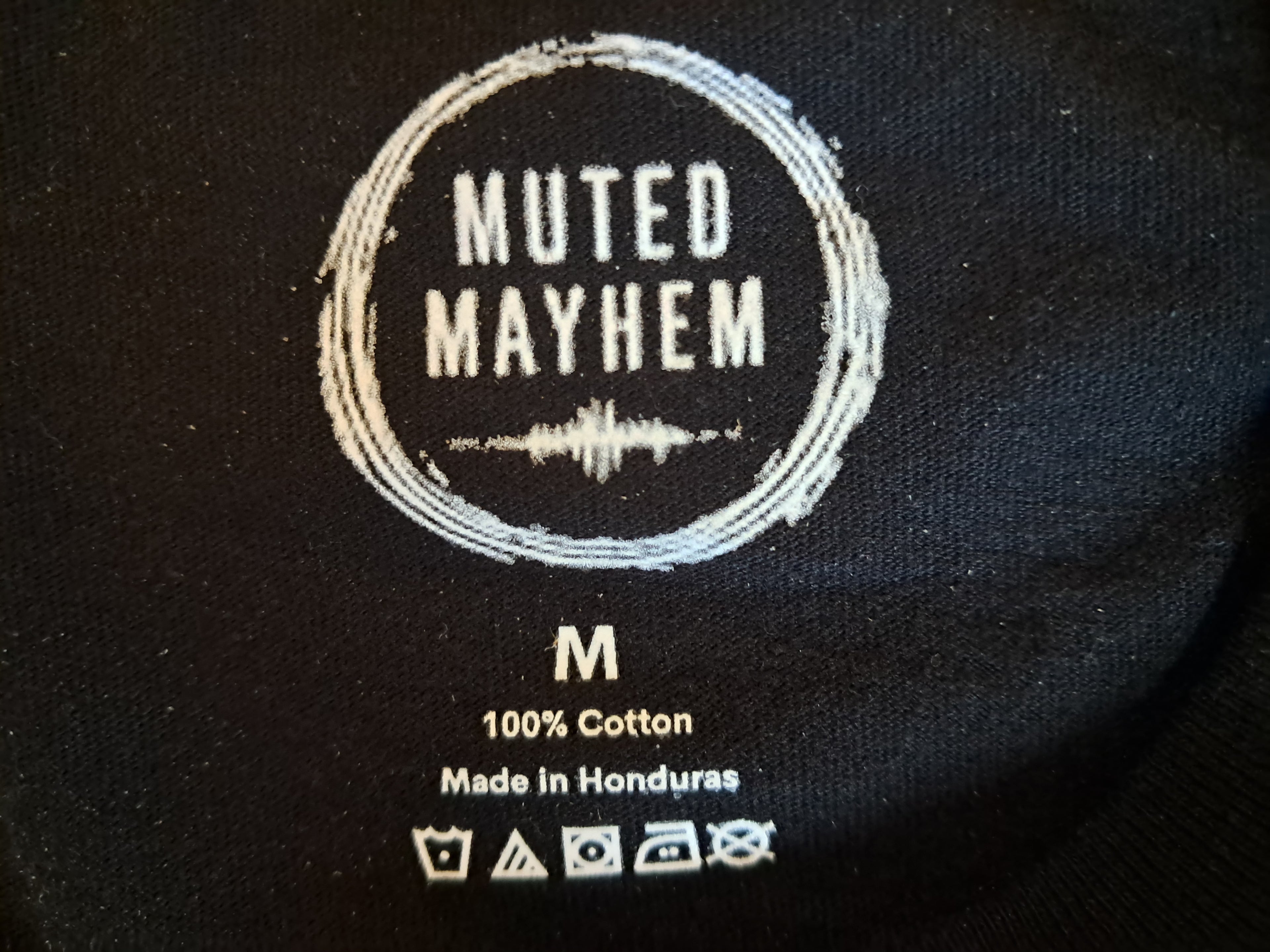 The logo neckline of a black tee promoting mental health and neurodivergence awareness by muted mayhem.