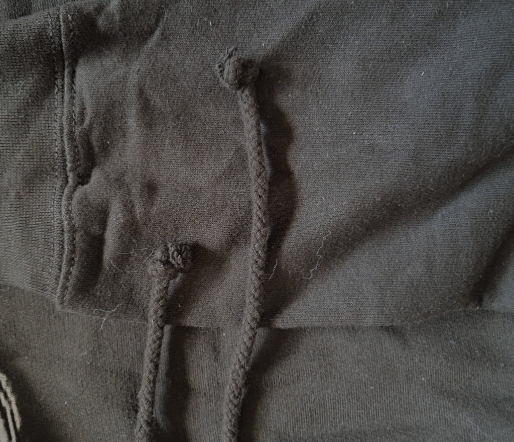Close-up of a dark charcoal gray fabric with thick braided drawstrings knotted at the top promoting mental health and neurodivergence awareness by muted mayhem